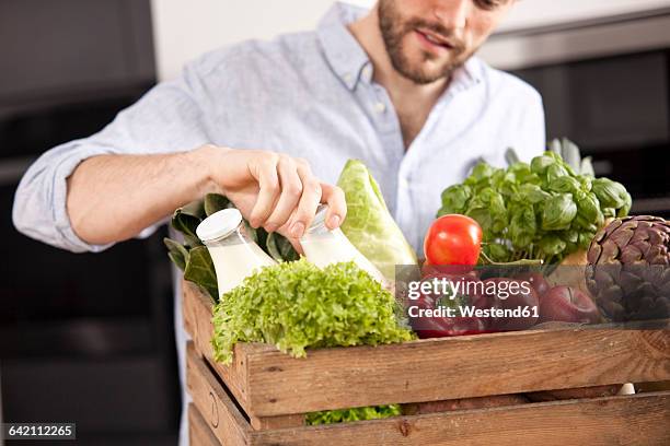 young man with wooden box of fresh vegetables and two milk bottles - arm made of vegetables stock pictures, royalty-free photos & images