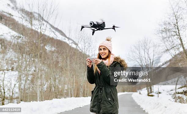 spain, asturias, young woman navigating a drone in the snowy mountains - クワッドコプター ストックフォトと画像