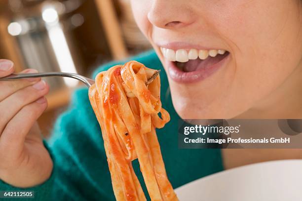 woman eating ribbon pasta with tomato sauce - tagliatelle foto e immagini stock