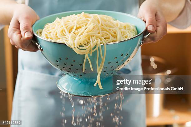draining cooked spaghetti - vergiet stockfoto's en -beelden