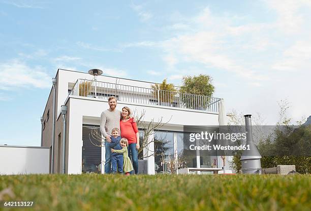 portrait of happy family with pregnant mother in garden - family of four in front of house stock-fotos und bilder