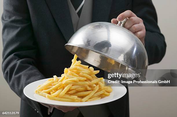 butler lifting serving dome from plate of chips - domed tray stock pictures, royalty-free photos & images