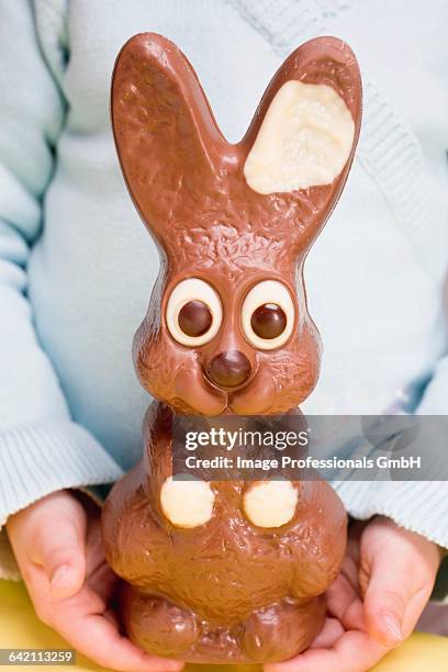 child holding large chocolate easter bunny - chocolate bunny stock pictures, royalty-free photos & images