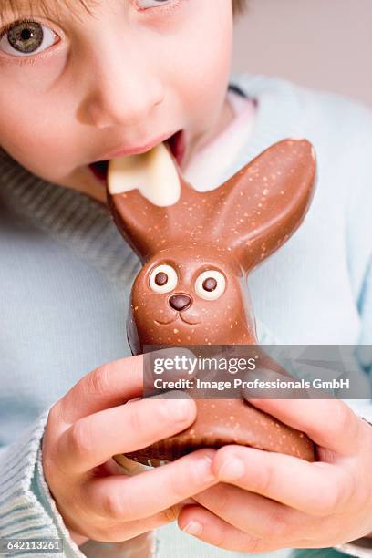 child biting into chocolate easter bunny - chocolate bunny stock pictures, royalty-free photos & images