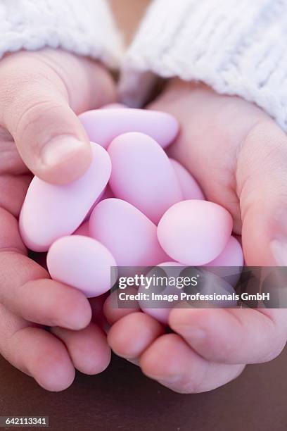 childs hands holding pink sugared almonds - sugared almond stock pictures, royalty-free photos & images