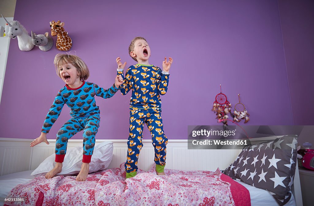 Brother and sister wearing pajamas romping around in children's room