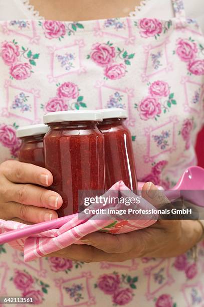 woman holding jars of jam, tea towel and kitchen spoon - strawberry jam stock pictures, royalty-free photos & images