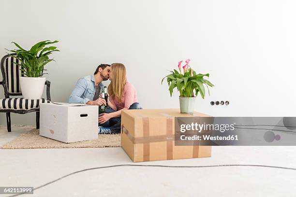 kissing couple sitting on the floor of their unfinished new home - teppich unfertig stock-fotos und bilder