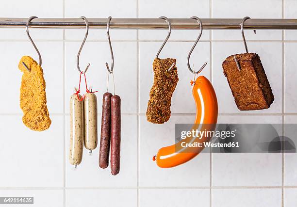 vegan and vegetarian sausages and steaks hanging on hooks - wurst stock-fotos und bilder