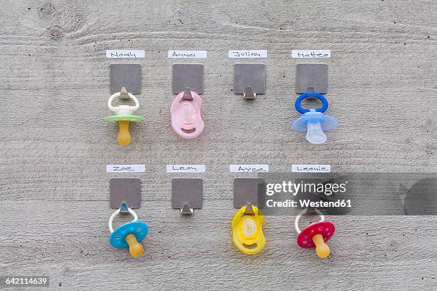 pacifiers hanging on concrete wall with name tags - daycare stock pictures, royalty-free photos & images