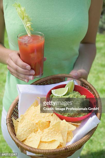 woman holding tomato drink & basket of guacamole & chips - americana aloe stock pictures, royalty-free photos & images