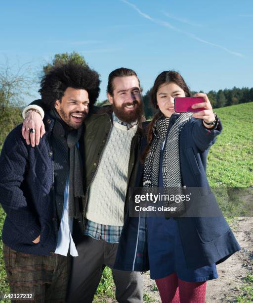 drie jonge volwassenen en een mobiele telefoon, vallen kleding - lypseuk2013 stockfoto's en -beelden