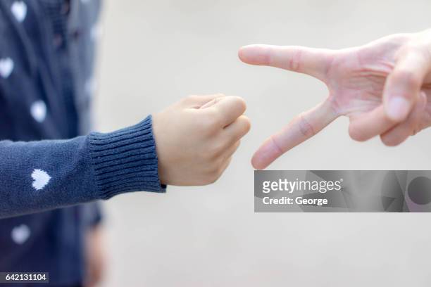 a girl and her mother playing a rock-paper-scissors game - rock paper scissors stock pictures, royalty-free photos & images