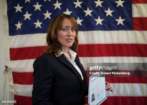 Rita Alejandra Alderete, originally from Argentina, stands for a picture holding her Certificate of Naturalization during a ceremony for new US...