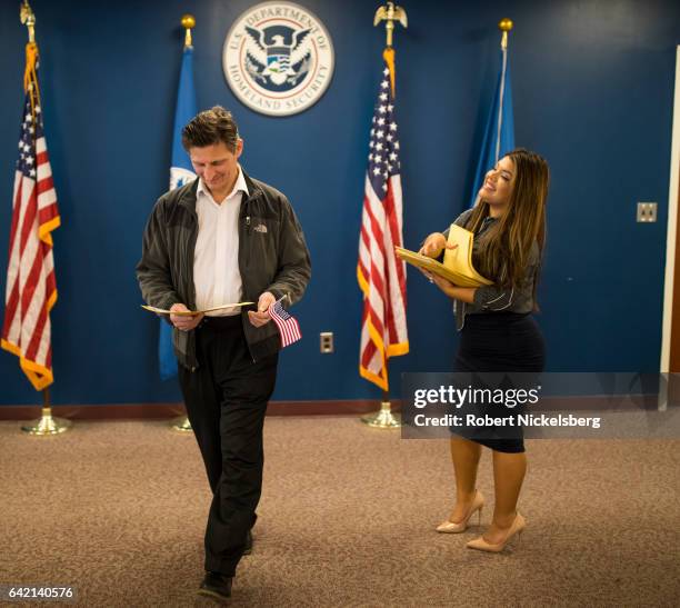 Man newly sworn in as a US citizen, left, receives his Certificate of Naturalization from a US government employee, right, during a naturalization...