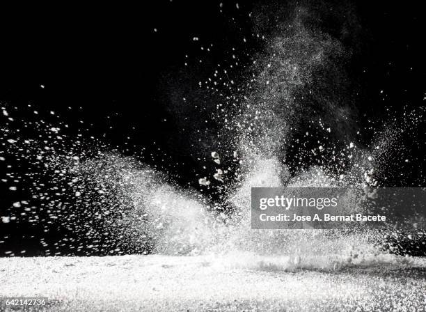 blackground of particles of white powder in ascending movement floating in the air produced by an impact - powder stock pictures, royalty-free photos & images