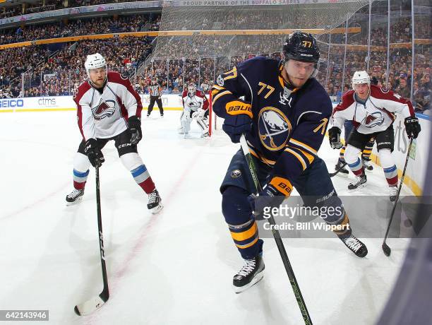 Dmitry Kulikov of the Buffalo Sabres controls the puck against Tyson Barrie and John Mitchell of the Colorado Avalanche during an NHL game at the...