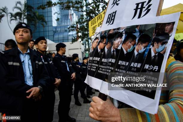 Police stand guard as pro-democracy supporters chant slogans and hold placards after the arrival of the seven police officers , who were found guilty...