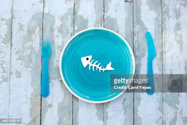 fish bone skeleton in a blue plate on table - animal bone stock pictures, royalty-free photos & images