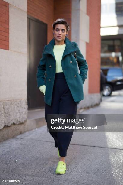 Guest is seen attending Marc Jacobs during New York Fashion Week wearing a green peacoat with yellow sweater and navy pants on February 16, 2017 in...