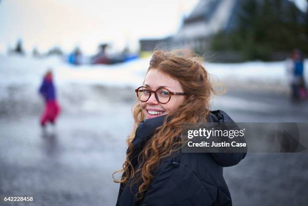 woman in a winter village looking happily at camera - eyeglasses winter stock pictures, royalty-free photos & images