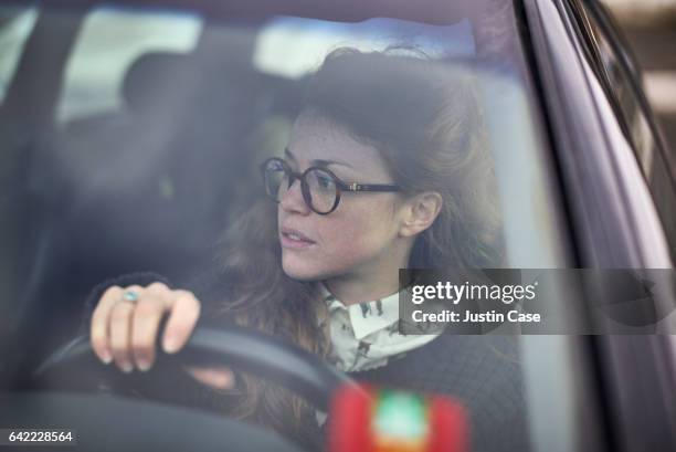woman wearing glasses steering her car - fahrschule stock-fotos und bilder