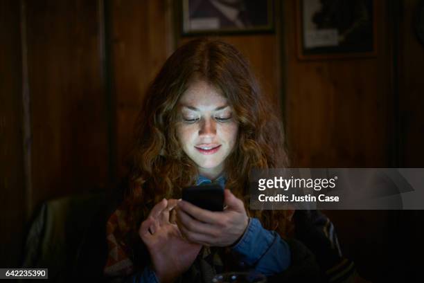 woman text messaging on her phone - sehen stock-fotos und bilder
