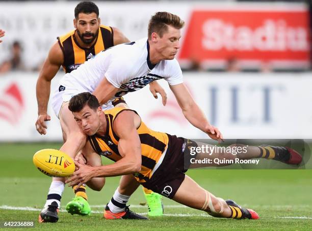 Jaeger O'Meara of the Hawks handballs whilst being tackled by Mark Blicavs of the Cats during the 2017 JLT Community Series match between the...