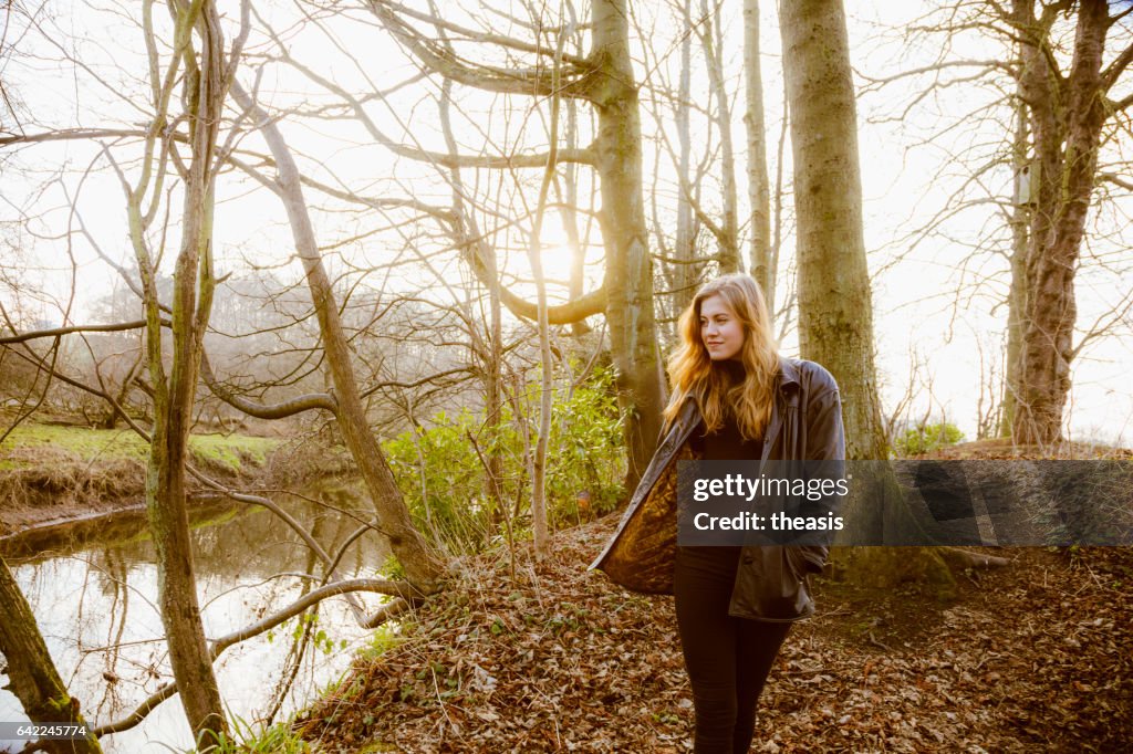 Beautiful young woman in black walking by a river