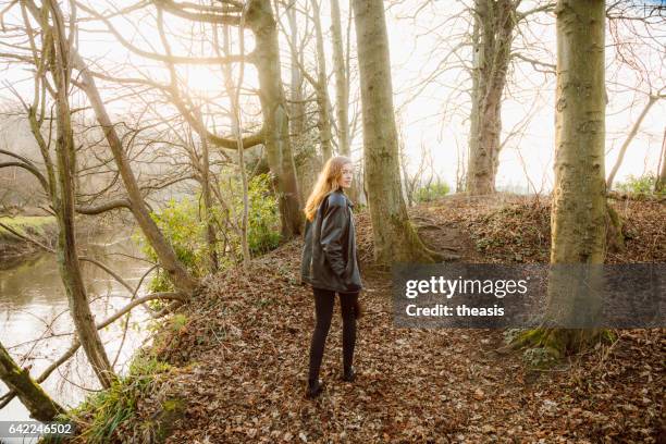 beautiful young woman in black walking by a river - theasis stock pictures, royalty-free photos & images