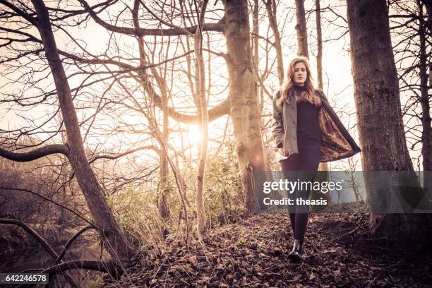 beautiful young woman in black walking by a river - theasis stock pictures, royalty-free photos & images