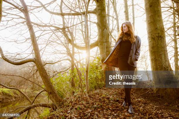 beautiful young woman in black walking by a river - theasis stock pictures, royalty-free photos & images