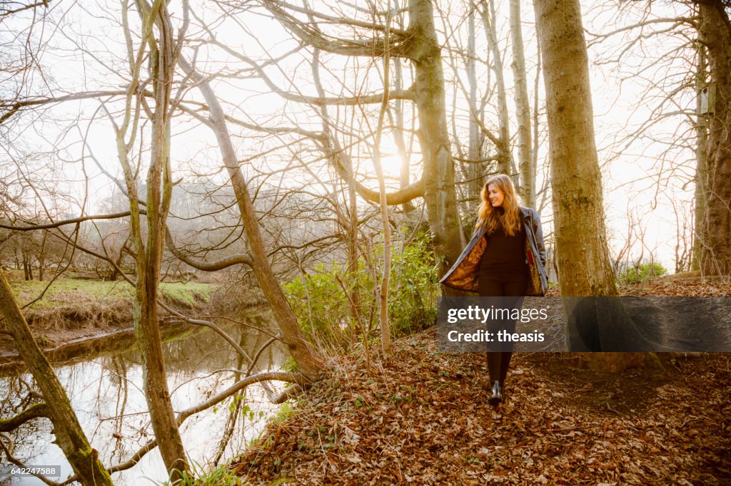 Beautiful young woman in black walking by a river