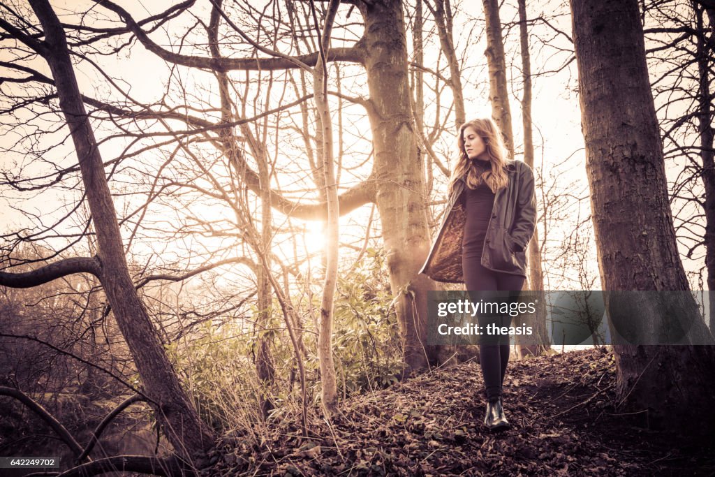 Beautiful young woman in black walking by a river