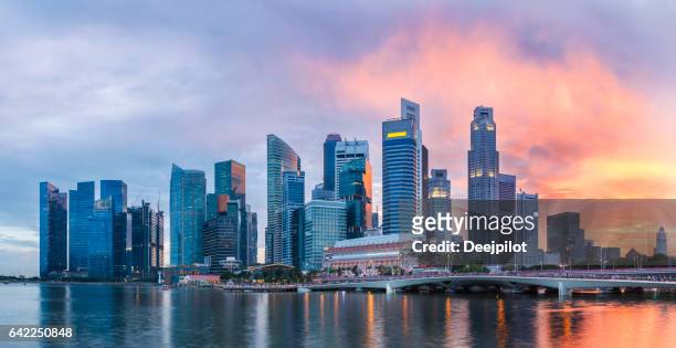 singapore skyline at marina bay at twilight with glowing sunset illuminating the clouds - singapore stock pictures, royalty-free photos & images