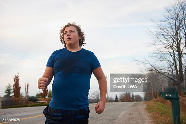 teen boy jogging on country road - teen boy shorts stockfoto's en -beelden