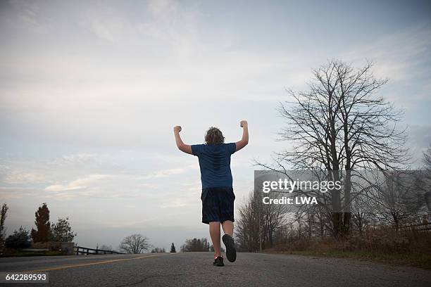 teen boy reaching top of hill - teen boy shorts stockfoto's en -beelden