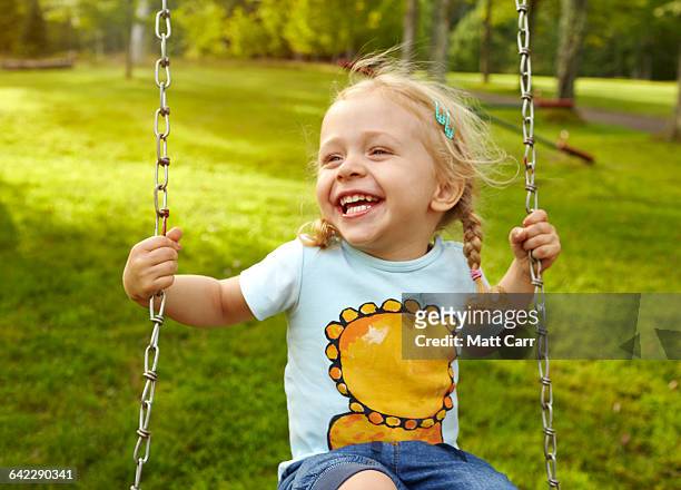 young girl laughing on swing - spielplatz einrichtung stock-fotos und bilder