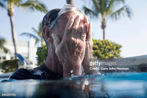 senior man splashing face in swimming pool - west palm beach stock pictures, royalty-free photos & images