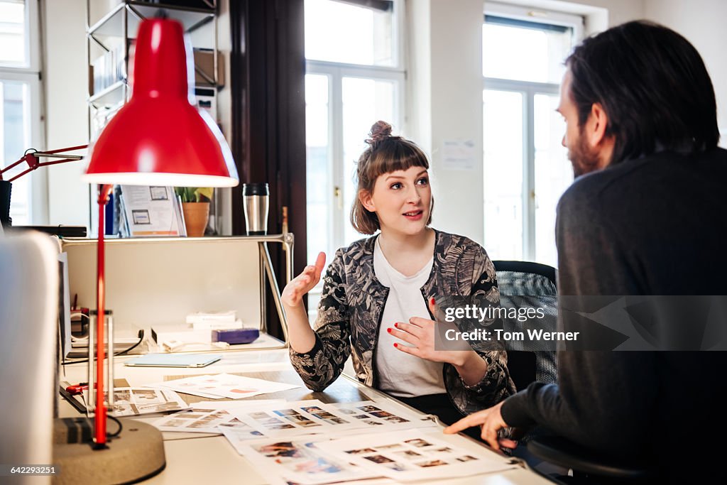 Young graphic designer talking with colleague