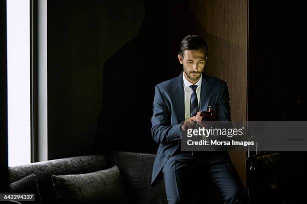 businessman using mobile phone in hotel room - premium with mobile stock-fotos und bilder