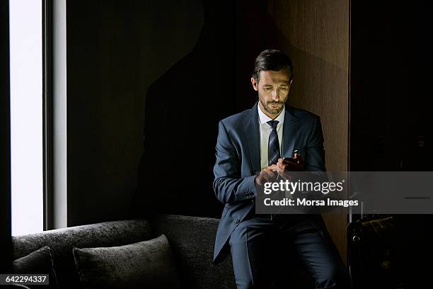 businessman using mobile phone in hotel room - wealthy man stock pictures, royalty-free photos & images