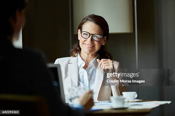 businesswoman looking at colleague during meeting - reichtum stock-fotos und bilder