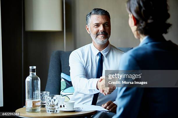 business people shacking hands after meeting - woman-man-handshake-across-table stock pictures, royalty-free photos & images