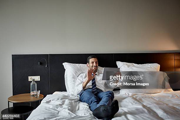 Businessman video calling on bed in hotel room