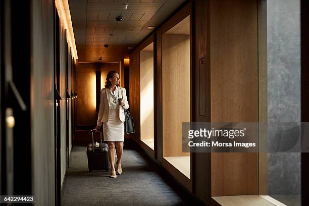 businesswoman with suitcase at hotel corridor - luxushotel stock-fotos und bilder