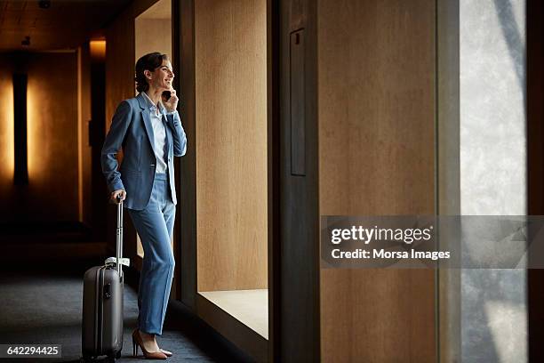 businesswoman talking on phone in hotel corridor - business travel stock pictures, royalty-free photos & images