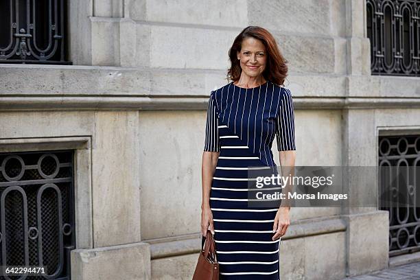 portrait of businesswoman against building - gestreiftes kleid stock-fotos und bilder