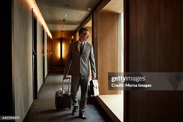 businessman walking in corridor at hotel - rolling luggage stock pictures, royalty-free photos & images