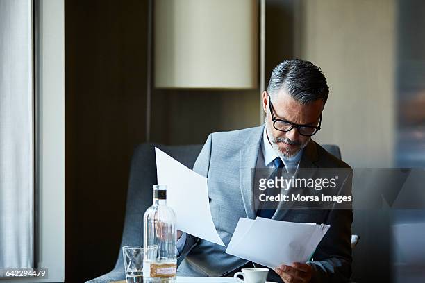 businessman reading documents in hotel room - finanzwirtschaft und industrie stock-fotos und bilder